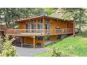 A-frame home with expansive wooden deck and matching wood siding surrounded by green grass and pines at 4923 Snowberry Ln, Evergreen, CO 80439