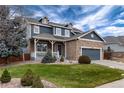 Charming two-story home with stone and siding, a cozy front porch, and a lush green lawn at 14669 Eagle River Run, Broomfield, CO 80023