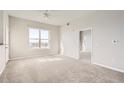 Well-lit living room featuring neutral paint, plush carpeting, and a large window showcasing the city view at 15475 Andrews Dr # 401, Denver, CO 80239