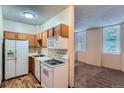 This kitchen features a white fridge, stove, and microwave, plus wood cabinets and an open view into the living room at 2225 Buchtel Blvd # 105, Denver, CO 80210