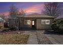 Charming single-story home with a brick facade, red door, landscaped yard, and a welcoming entrance at 1654 Valentia St, Denver, CO 80220
