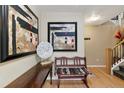 Inviting entryway featuring modern art, wooden bench, and hardwood floors leading to the staircase at 476 S Saulsbury St, Lakewood, CO 80226