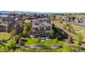 Aerial view of backyard with deck, patio, fire pit, green lawn, split rail fence and beautiful landscaping at 1240 Starglow Pl, Highlands Ranch, CO 80126