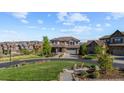 Beautifully landscaped front yard with lush green lawn, mature trees and a charming seating area at 1240 Starglow Pl, Highlands Ranch, CO 80126