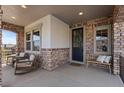 Inviting covered front porch featuring brick accents, seating, and a welcoming wreath on the front door at 1240 Starglow Pl, Highlands Ranch, CO 80126