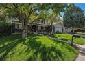 Well maintained front yard with mature trees shading a path leading to the entryway at 7622 E Nassau Ave, Denver, CO 80237