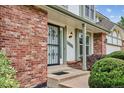 Front porch with brick detail, green trim, secure front door and manicured bushes at 8182 Sweet Water Rd, Lone Tree, CO 80124