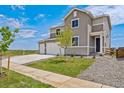 Attractive gray home boasting a three-car garage, front yard with young trees, and easy access via a sidewalk at 14412 Heritage Dr, Mead, CO 80504