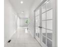 Bright hallway features tile floors, white walls and glass paneled doors with a glimpse into a sunlit room at 6387 Agave Ave, Castle Rock, CO 80108