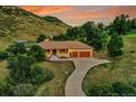A beautiful aerial view of a brick house nestled in a lush, green landscape with mountain views at 5808 Crestbrook Cir, Morrison, CO 80465
