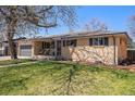 This brick home features an attached garage and cozy front porch at 241 S 15Th Ave, Brighton, CO 80601