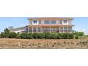 Exterior showcasing a deck, mature bushes, large windows, and farmland around the home at 3160 Bella Rosa Pkwy, Longmont, CO 80504