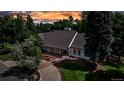 Beautiful home surrounded by lush trees, showcasing its elegant exterior and landscaped yard at sunset at 17 E Belleview Ln, Greenwood Village, CO 80121