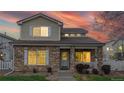Charming two-story home featuring a stone facade, covered porch, and warm exterior lights at 11738 Zenobia Loop, Westminster, CO 80031