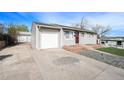 View of gray house with an attached one car garage, updated windows and a front yard with rock and turf at 8441 Mcdougal St, Denver, CO 80229