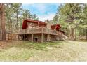 Spacious home with a large wooden deck and stone foundation, surrounded by a serene wooded landscape at 1150 Fremont Dr, Larkspur, CO 80118