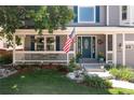 Inviting front porch with a charming American flag, decorative flower pots, and seating area at 1774 Spring Water Pl, Highlands Ranch, CO 80129