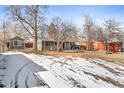 Expansive backyard with a detached structure, lawn, and visible tire tracks in the partial snow cover at 1171 S Perry St, Denver, CO 80219