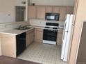 Traditional kitchen features white appliances, light wood cabinets and a black gas range at 9913 E Carolina Cir # 203, Denver, CO 80247