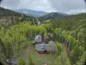 An aerial view showcasing the home nestled in the forest and surrounding mountains at 2720 S Spring Gulch Rd, Idaho Springs, CO 80452
