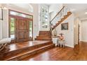 Elegant home foyer featuring a wood front door, staircase, hardwood floors, and ample natural light at 20496 Stonewood Trl, Morrison, CO 80465