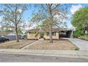 Inviting home exterior with mature trees, rock landscaping, and a convenient carport at 6953 Elati Way, Denver, CO 80221