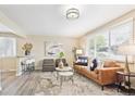 Comfortable living room with modern decor, a brown leather sofa, and natural light from the window at 6953 Elati Way, Denver, CO 80221
