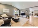 Cozy living room featuring a vaulted ceiling, hardwood floors, a plush sofa, and a decorative fireplace at 904 Fieldstone Pl, Highlands Ranch, CO 80126