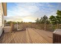Spacious wooden back deck perfect for entertaining, featuring wood railings and space for seating, with sunset background at 3087 Deer Creek Trl, Highlands Ranch, CO 80129