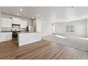 Open-concept living area featuring wood floors transitioning to carpet, with a modern kitchen and bright natural light at 3004 Oxley St, Strasburg, CO 80136