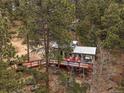 Exterior view of a cabin with a red deck, seating, and peaceful mountain views at 26349 Pleasant Park Rd, Conifer, CO 80433