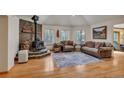 Cozy living room with wood floors, comfortable seating, and a stone fireplace with a wood-burning stove at 9590 S Warhawk Rd, Conifer, CO 80433