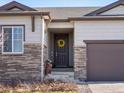 Charming front door with yellow wreath, brown trim, stone accents, and welcoming entrance at 17880 Weymouth Ave, Parker, CO 80134