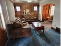 Inviting living room featuring wood-paneled walls, classic furnishings, and plush carpeting at 3036 W Clyde Pl, Denver, CO 80211
