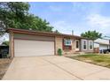 Tan home featuring a brick facade and attached one car garage with well-kept lawn at 5167 Sable St, Denver, CO 80239