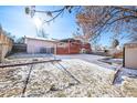 Fenced backyard featuring a deck, shed, and a spacious yard partially covered with snow at 16505 E Arkansas Ave, Aurora, CO 80017