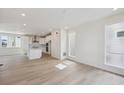 Open-concept kitchen features white cabinetry, island, stainless appliances, and wood floors at 1257 Rhett Dr, Erie, CO 80026