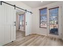 Bedroom with light wood floors, barn door to closet, and door to outdoor deck at 13640 E Iliff Pl, Aurora, CO 80014
