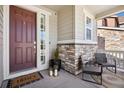 Close-up of front porch with chairs, brick accents, and a charming welcome mat at the front door at 1043 S Fultondale Ct, Aurora, CO 80018