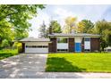 A well maintained brick house featuring an attached garage, and a vibrant green lawn at 1757 S Van Dyke Way, Lakewood, CO 80228