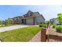 Attractive home with a two-car garage, stone and siding facade, lush lawn, and a charming wooden fence at 9350 Dunraven St, Arvada, CO 80007