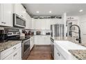Gourmet kitchen with white cabinetry, granite countertops, stainless steel appliances, and hardwood floors at 9350 Dunraven St, Arvada, CO 80007