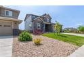 Well-maintained front yard features decorative rock landscaping and lush green grass leading to a stone accented home at 9350 Dunraven St, Arvada, CO 80007