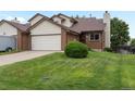 Two-story home with a brick and vinyl exterior, featuring an attached garage and well-maintained lawn at 2040 Yarrow St, Lakewood, CO 80214