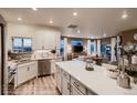 Bright, modern kitchen with white cabinets, quartz countertops, island, and views of the living room at 900 W 128Th Pl, Westminster, CO 80234