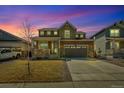 Charming two-story home featuring stone accents, a covered porch, a two-car garage, and a well-manicured lawn at 892 High Point Trl, Elizabeth, CO 80107