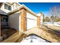 Exterior of a two-car garage with brick accents and a snow-covered yard in a residential neighborhood at 3383 Mount Royal Dr # 46, Castle Rock, CO 80104