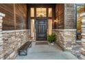 Inviting front entrance with a dark wood door, stone accents, sidelights, and a charming bench at 2597 Oak Vista Ct, Castle Rock, CO 80104