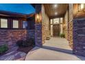 Inviting front porch with stone pillars, wood accents, and a grand entrance door at 2597 Oak Vista Ct, Castle Rock, CO 80104