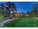Well-manicured front yard at dusk featuring lush green grass, mature trees, and landscape lighting at 2597 Oak Vista Ct, Castle Rock, CO 80104